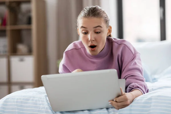 Chica sorprendida con ordenador portátil en casa —  Fotos de Stock
