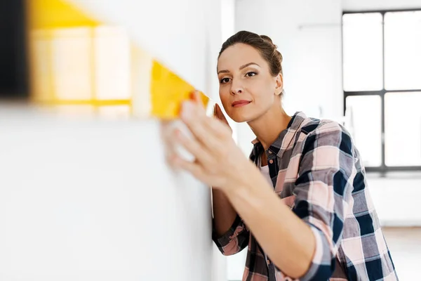 Gelukkig vrouw met niveau meten muur thuis — Stockfoto