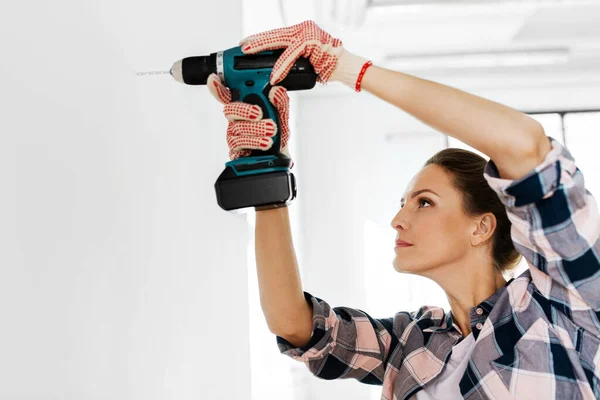Vrouw met perforator boren muur thuis — Stockfoto