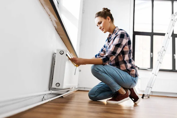 Woman with ruler measuring heater at home — Stock Photo, Image