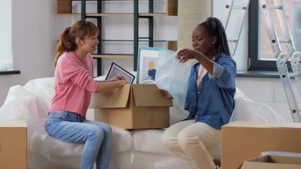 Ženy stěhují do nového domova a vybalují krabice — Stock video