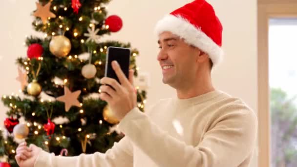 Hombre con teléfono que tiene videollamada en el árbol de Navidad — Vídeos de Stock