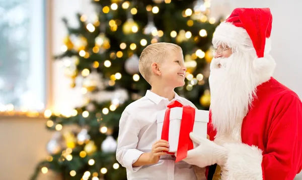 Uśmiechnięty chłopiec z Mikołajem i prezenty w domu — Zdjęcie stockowe