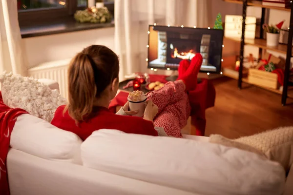 Nő néz TV-t tejszínnel és mályvacukorral karácsonykor — Stock Fotó