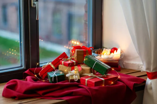 Kerstcadeaus op rood tafelkleed op vensterbank — Stockfoto