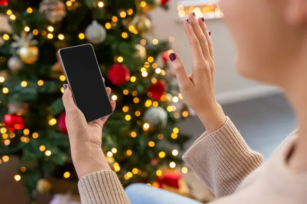 スマートフォンを持つ女性はクリスマスにビデオ通話をします — ストック写真