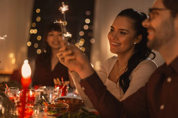 Happy friends with sparklers at christmas dinner — Stock Photo, Image