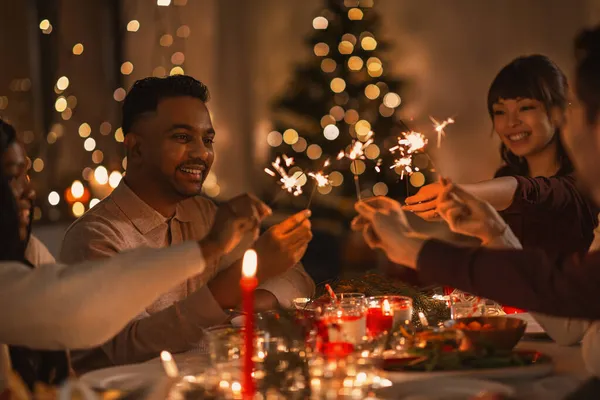Amigos felices con bengalas en la cena de Navidad — Foto de Stock