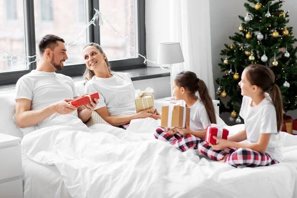 Happy family with christmas gifts in bed at home — Stock Photo, Image
