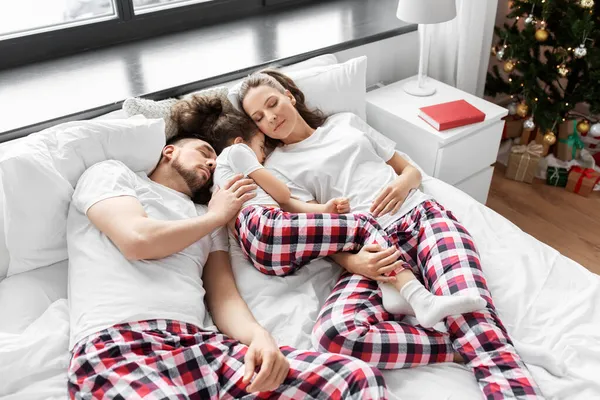 Feliz familia durmiendo en la cama en la mañana de Navidad —  Fotos de Stock