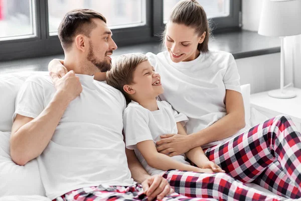 Счастливая семья в пижаме в постели по утрам — стоковое фото