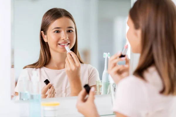Tonårstjej som applicerar läppstift i badrummet — Stockfoto