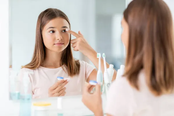 Teenage girl applying contact lenses at bathroom — Stock Photo, Image