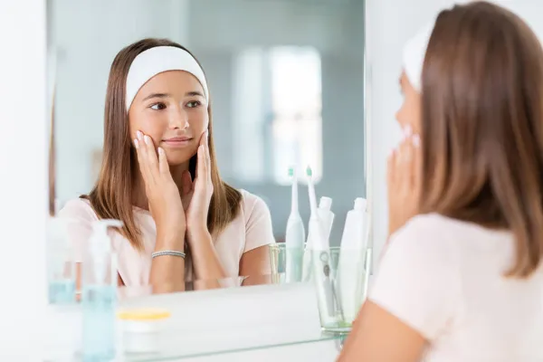 Adolescente olhando no espelho no banheiro — Fotografia de Stock