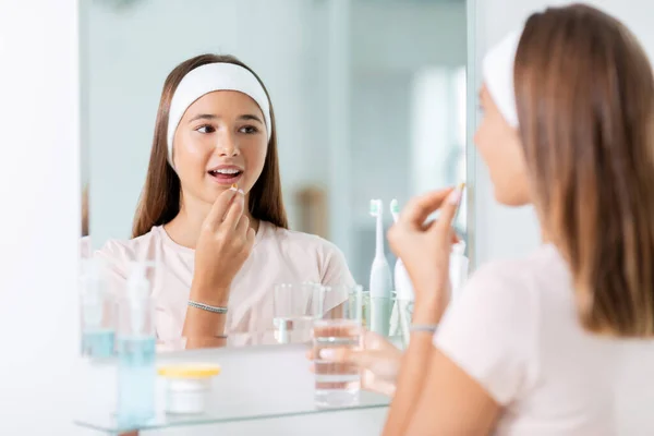 Teenage girl taking cod liver oil at mirror — Stock Photo, Image