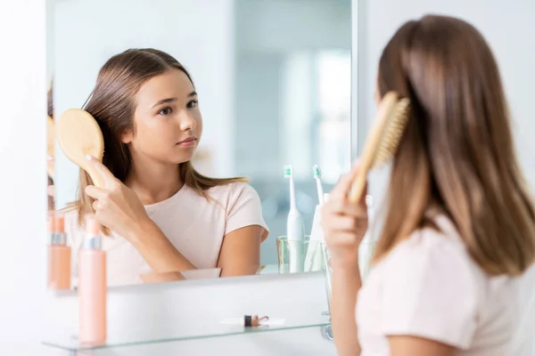Chica adolescente cepillando el cabello con peine en el baño — Foto de Stock