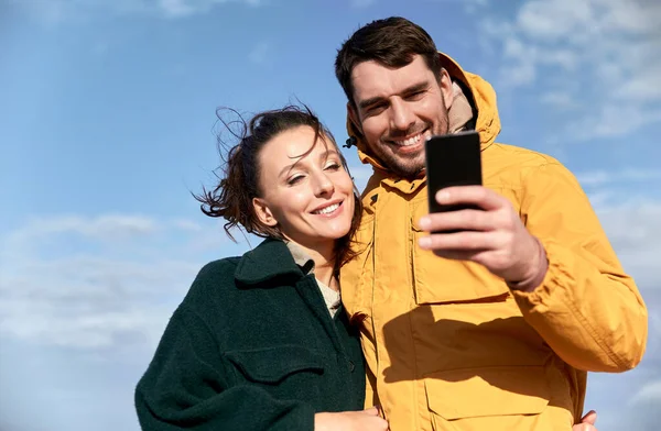 在秋天的海滩上与智能手机的情侣 — 图库照片