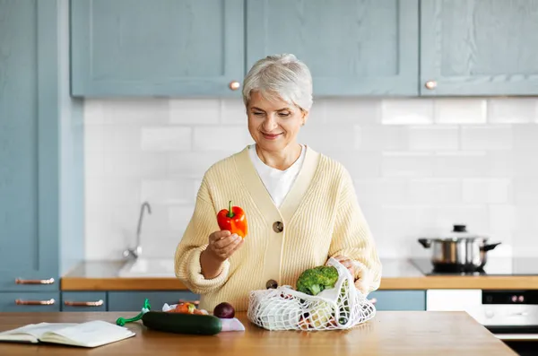 Жінка з овочами і куховарською книгою на кухні — стокове фото