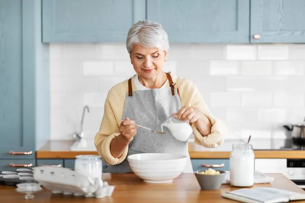 Счастливая женщина готовит еду на кухне дома — стоковое фото