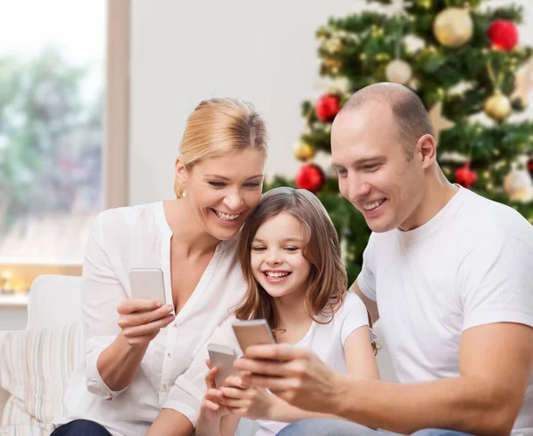 Familia feliz con teléfonos inteligentes en casa en Navidad — Foto de Stock