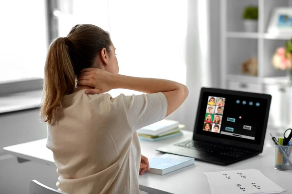Tired teacher with laptop touching neck at home — Stock Photo, Image