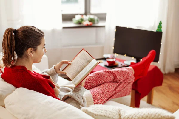 Молода жінка читає книгу вдома на Різдво — стокове фото