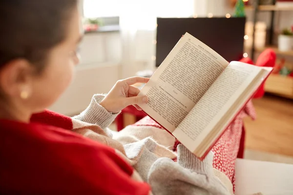 Giovane donna che legge il libro a casa a Natale — Foto Stock