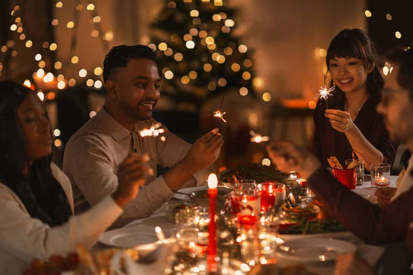 Boldog barátok csillagszórókkal a karácsonyi vacsorán — Stock Fotó