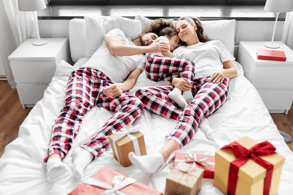 Glückliche Familie schläft am Weihnachtsmorgen im Bett — Stockfoto