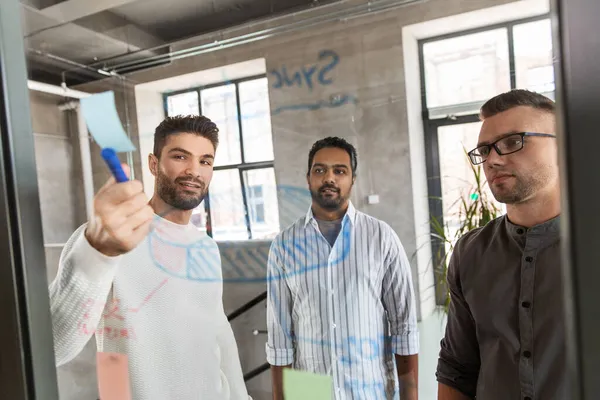 Mannen die werken met kaarten op glasplaat op kantoor — Stockfoto