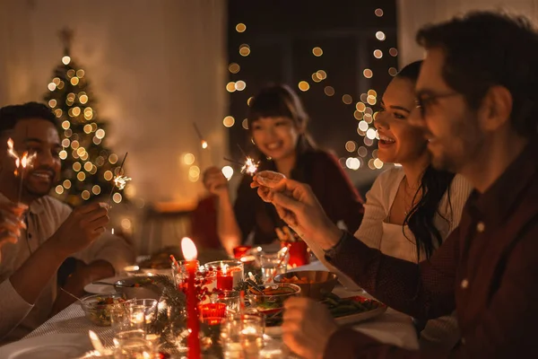 Amigos felizes com faíscas no jantar de Natal — Fotografia de Stock