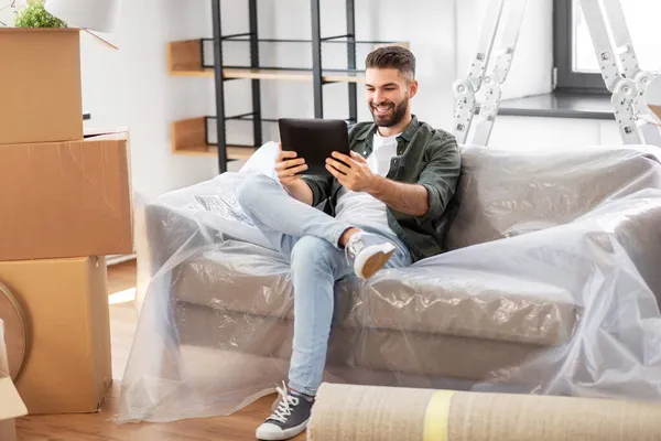 Hombre con la tableta PC y cajas que se mueven en el nuevo hogar —  Fotos de Stock