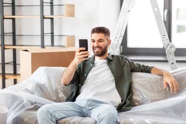 Homme avec smartphone et boîtes déménageant dans une nouvelle maison — Photo