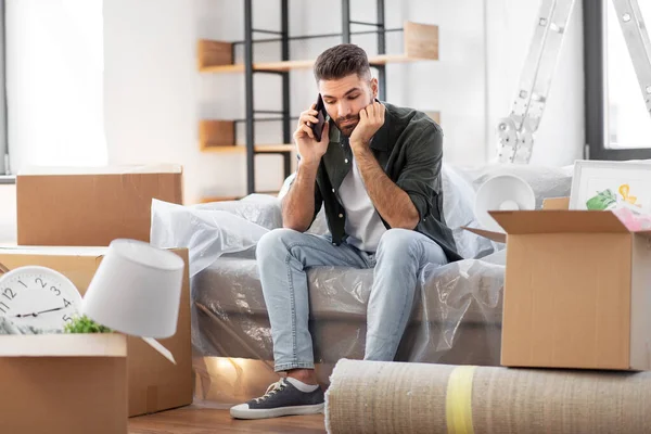 Triste hombre llamando en el teléfono inteligente de mudanza a nuevo hogar —  Fotos de Stock