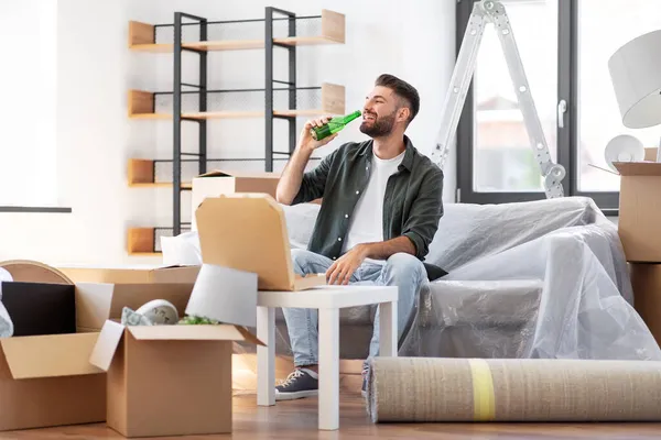 Mężczyzna z pudełkiem pizzy i butelki piwa w nowym domu — Zdjęcie stockowe