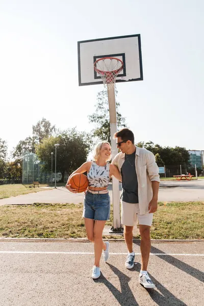 Счастливая пара с мячом на баскетбольной площадке — стоковое фото