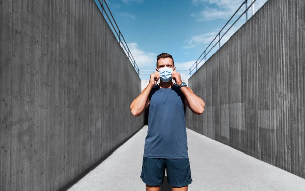 Young man in medical mask doing sports outdoors — Stock Photo, Image