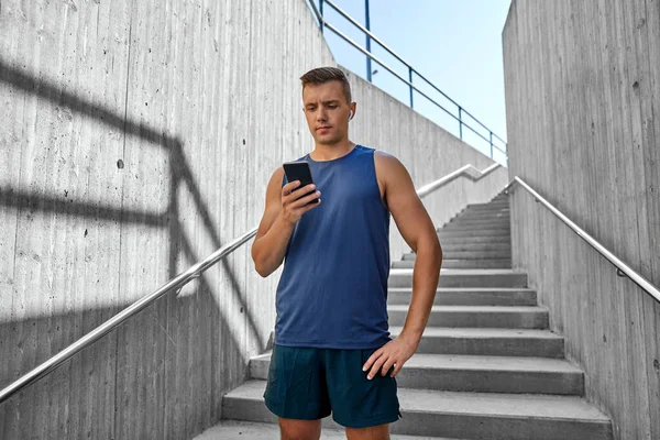 Joven atleta hombre con auriculares y teléfono inteligente —  Fotos de Stock