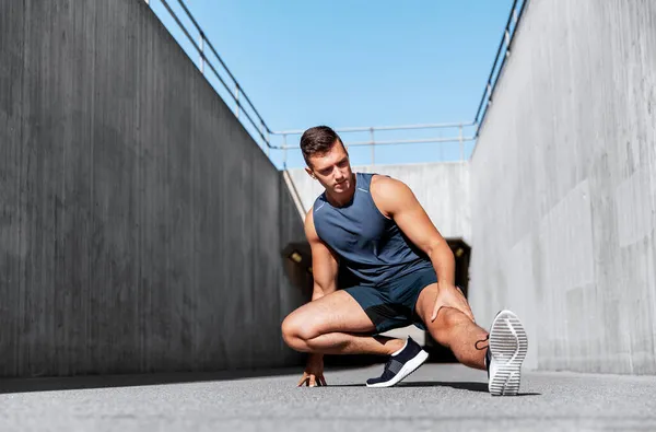 Man doing sports and stretching leg outdoors — Stock Photo, Image