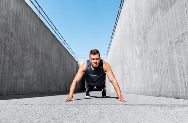 Young man doing push ups on city street — Stock Photo, Image