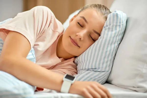 Chica con reloj inteligente durmiendo en la cama en casa — Foto de Stock