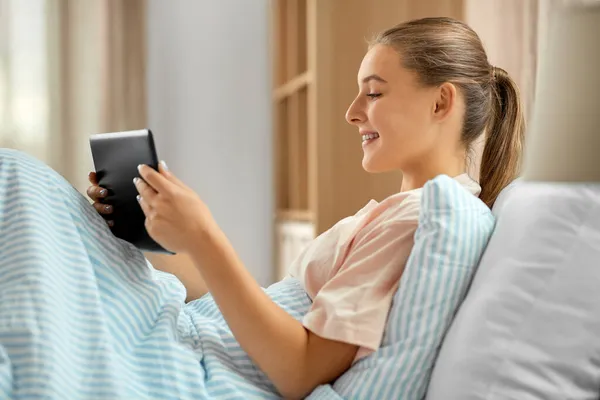 Gelukkig meisje met tablet pc in bed thuis — Stockfoto