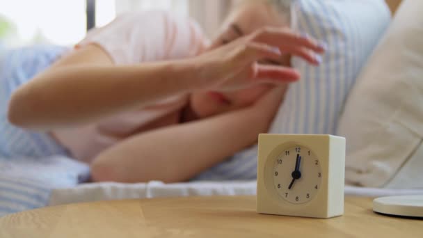 Menina sonolenta com despertador despertando na cama — Vídeo de Stock