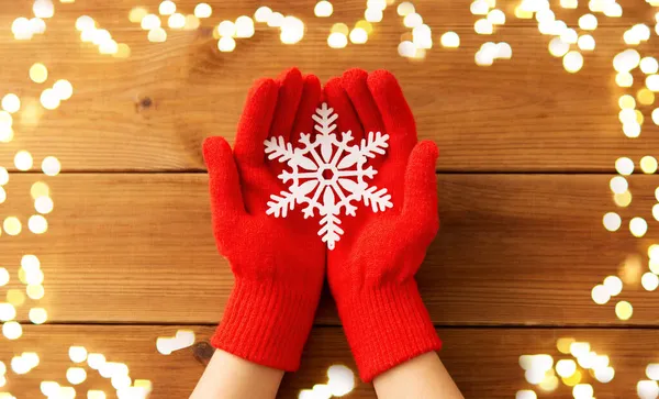 Manos en guantes de lana roja sosteniendo gran copo de nieve — Foto de Stock