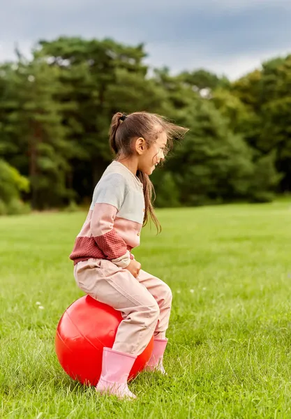 Szczęśliwy mała dziewczyna odbija się na hopper piłkę w parku — Zdjęcie stockowe