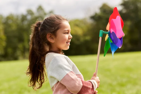 Szczęśliwa dziewczynka z pinwheel gra w parku — Zdjęcie stockowe