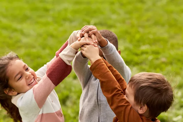 Happy children playing and stacking hands at park — Stock Photo, Image