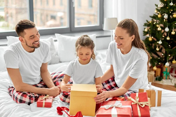 Famiglia felice con regali di Natale a letto a casa Immagini Stock Royalty Free