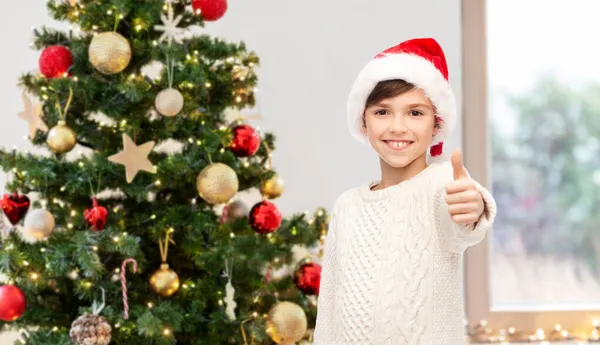 Menino feliz mostrando polegares para cima sobre árvore de natal — Fotografia de Stock