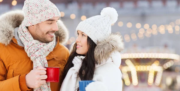 Couple heureux avec des tasses à thé sur les lumières de Noël — Photo